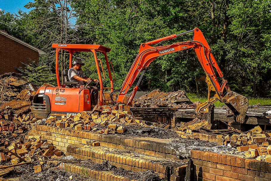Kubota Mini Excavator demolishing sub-floor and foundation in burned residential home. Image by W.C. Black and Sons, Inc.